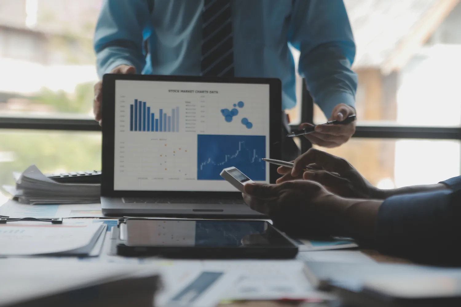 Financial analysts analyze business financial reports on a digital tablet planning investment project during a discussion at a meeting of corporate showing the results of their successful teamwork.