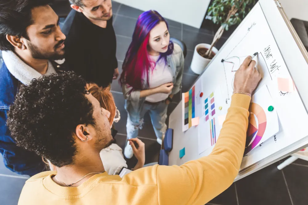 Group of multi ethnic executives discussing during a meeting. Business man and woman sitting around table at office and smiling. A team of young creative designers